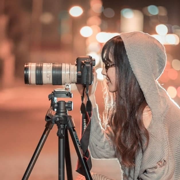 Image d'une photographe, de profil, prenant une photo avec son appareil 